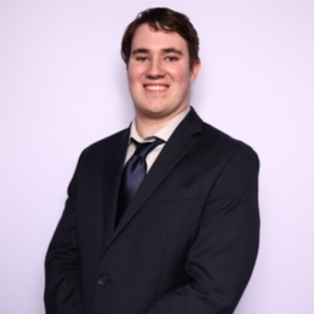 Headshot of Connor Shaw, Consulting Analyst at ProInfoNet, smiling and wearing a suit in front of a lavender background.