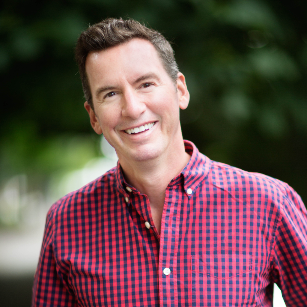 Headshot of Jon Leslie, Director of Consulting at ProInfoNet, smiling and wearing a red checkered button-down shirt outdoors.
