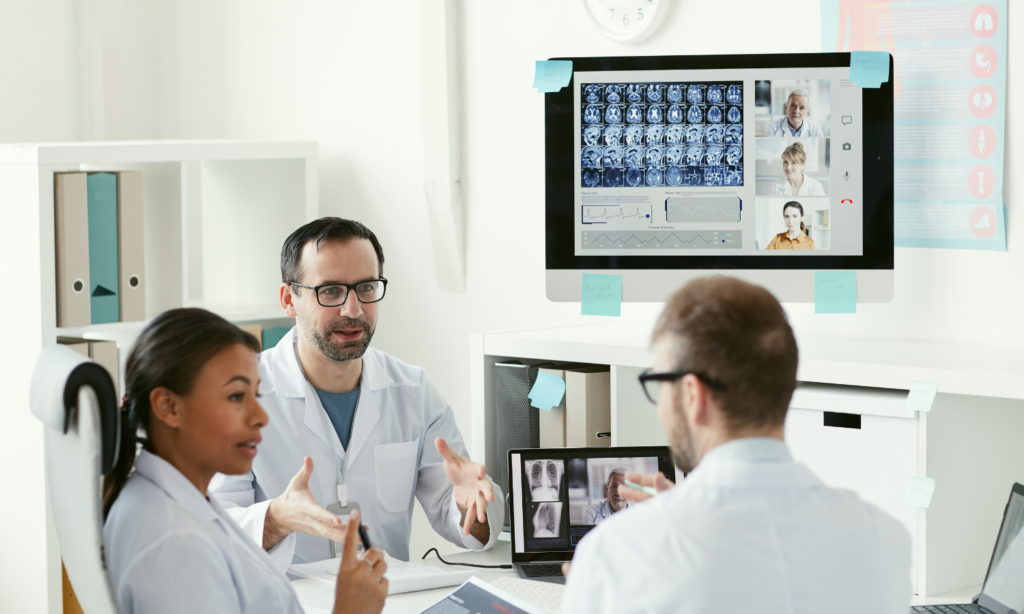 Healthcare team reviewing medical images and patient data on screens during a clinical meeting